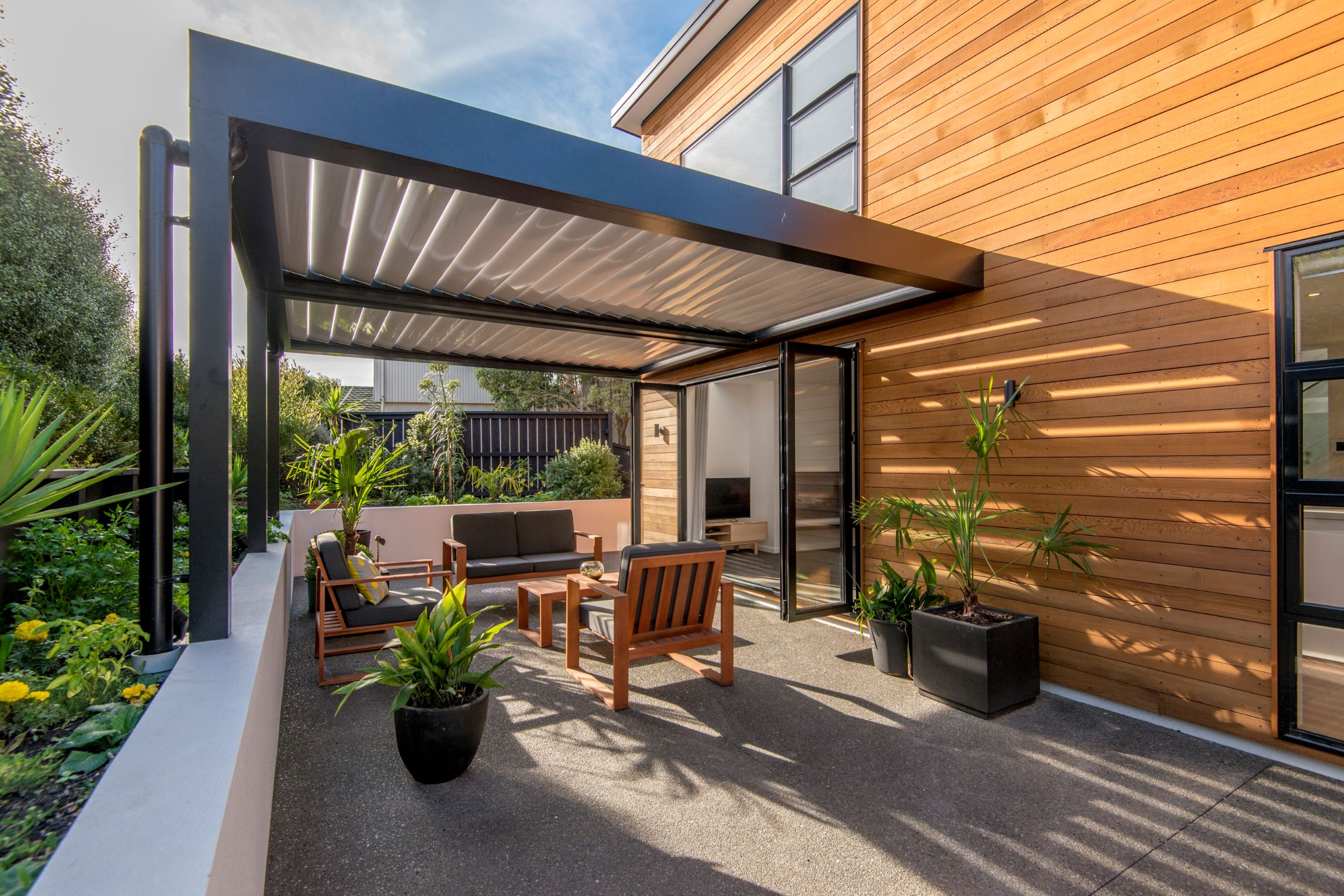 townhouse-courtyard-exposed-concrete-patio-louvre-roof-cedar-weatherboard-garden